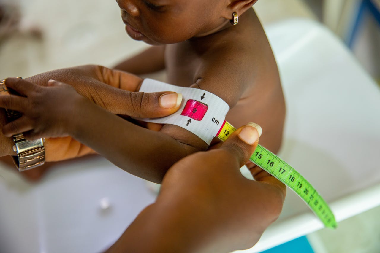 Crafting Captivating Headlines: Your awesome post title goes here A healthcare professional measures a child's arm using MUAC tape for malnutrition assessment.